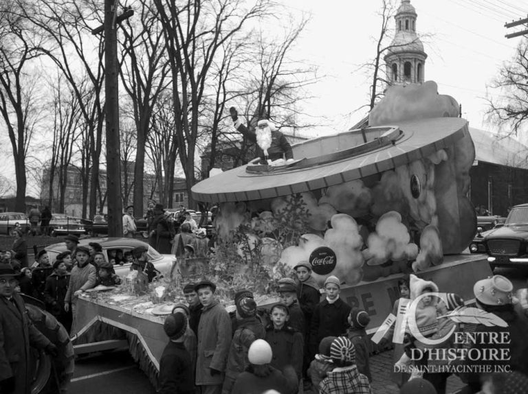 Le Père Noël en soucoupe volante!1960. - Fonds Raymond Bélanger, CH548.Vers la fin des années 1940, le Père Noël arrive par train à Saint-Hyacinthe. En 1955, il fait son arrivée en hélicoptère et, en 1960, il défile dans sa soucoupe volante! Du moins, c'est ce qu'en dise les journaux... Cette année-là, les rennes du Père Noël étaient en congé semble-t-il...